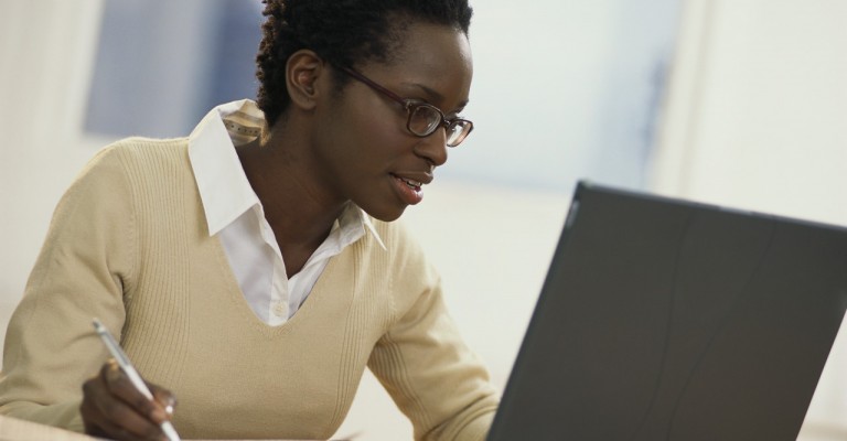 Young Woman with Newspaper Using Laptop